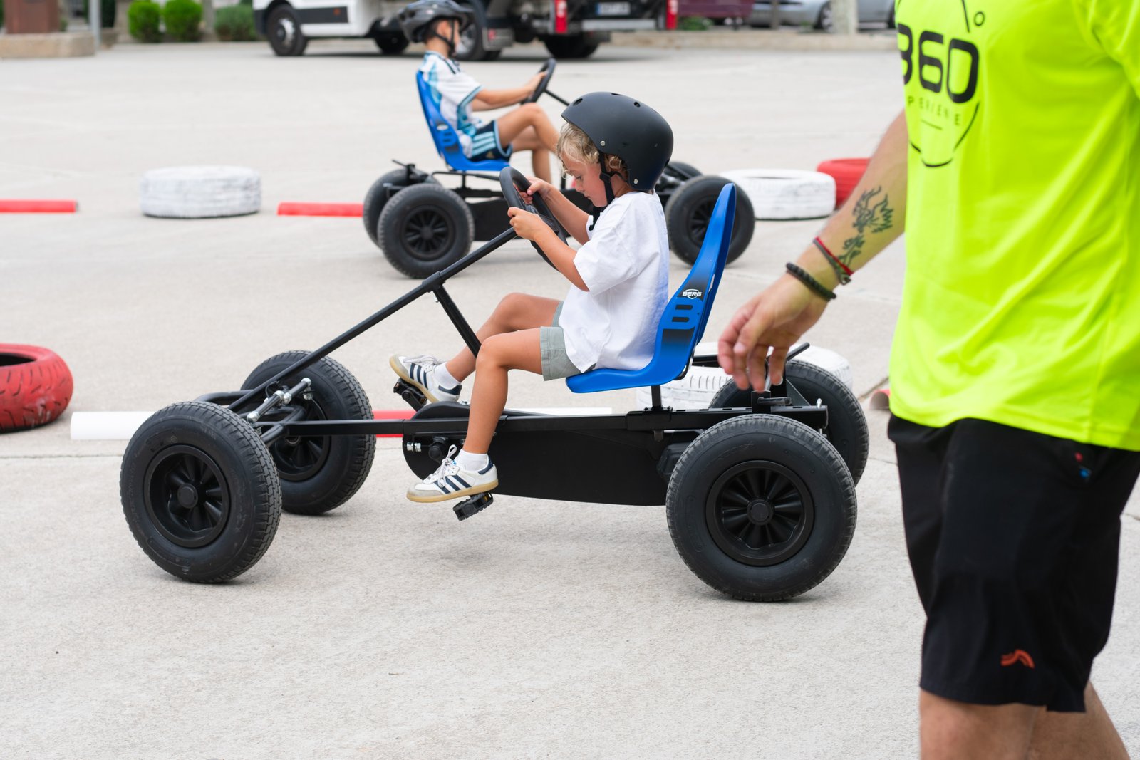Niños en karts a pedales durante una fiesta familiar con supervisión de monitores