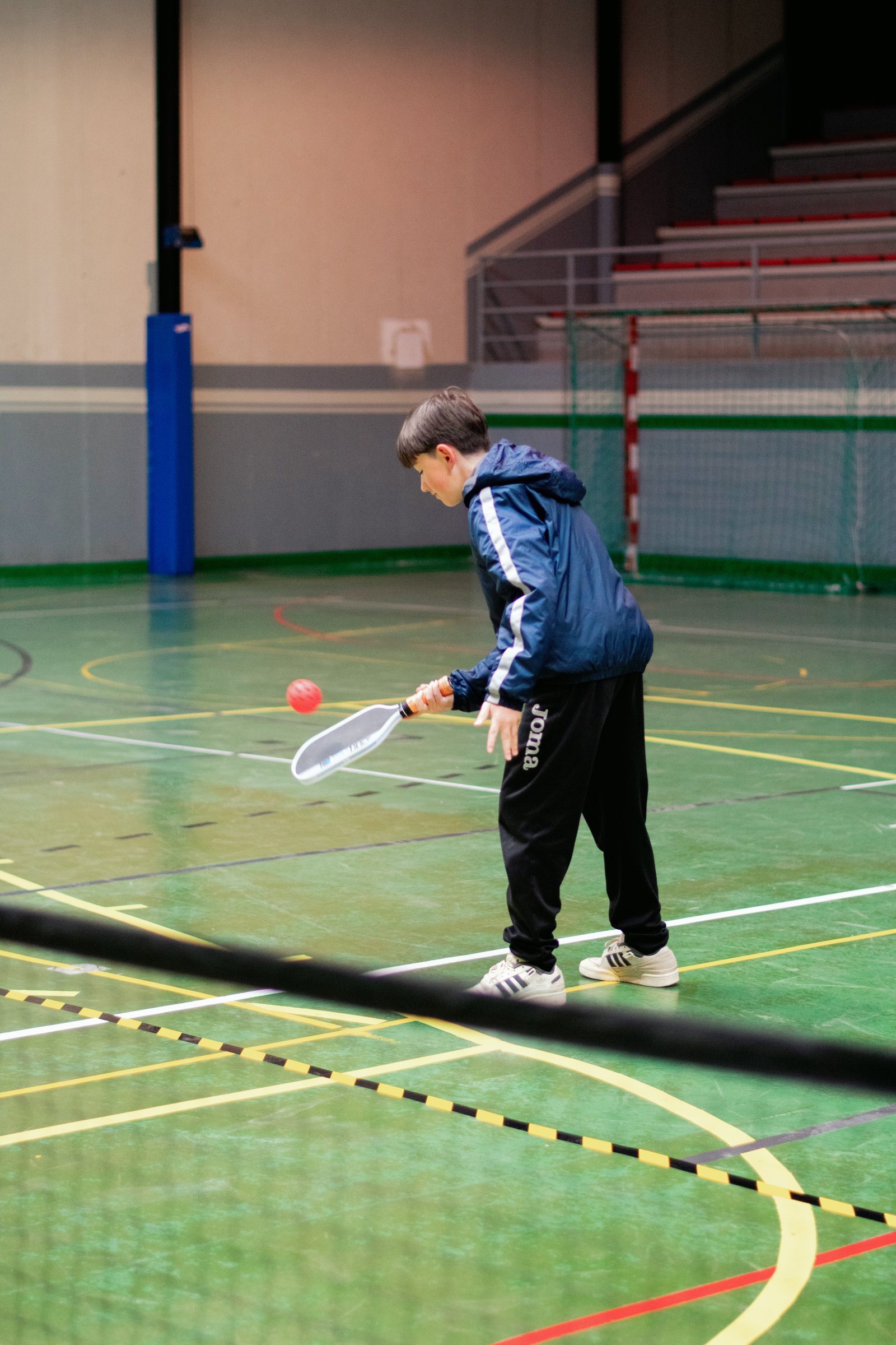 Niño jugando a pickleball en una pista cubierta