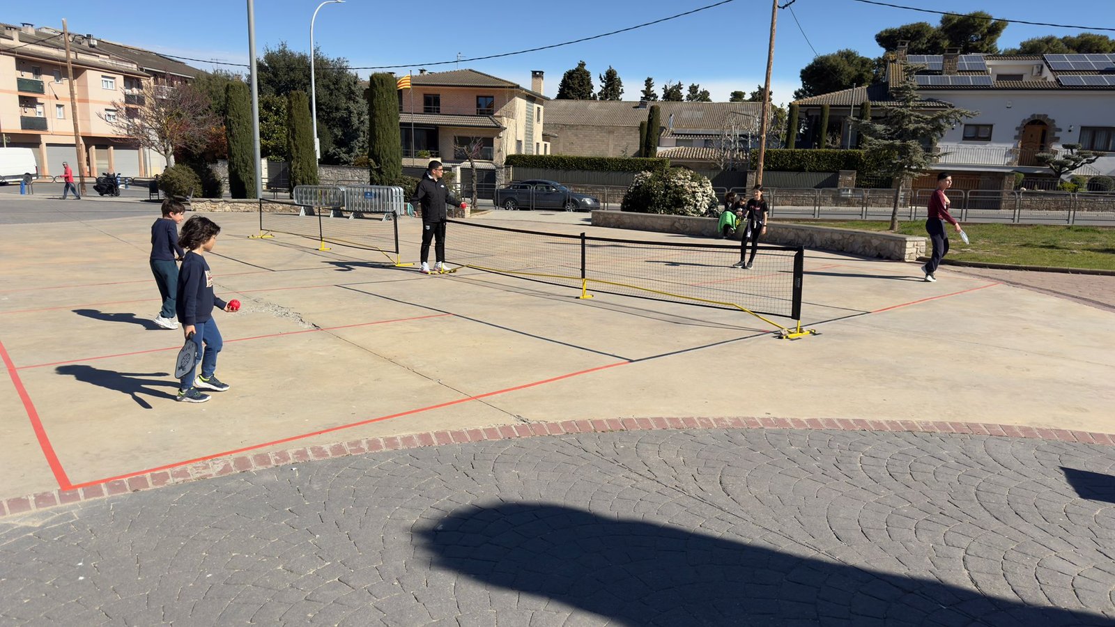 Niños participando en una jornada de pickleball en una plaza
